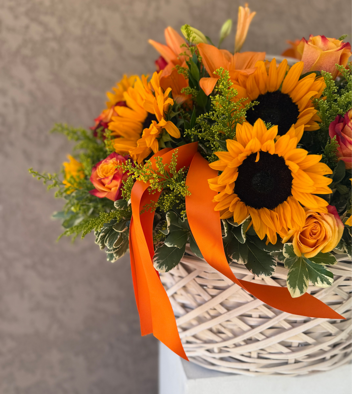 Bouquet of sunflowers and orange roses with an orange ribbon on a neutral background