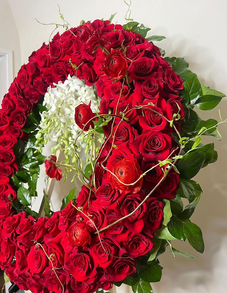 Floral wreath made of red roses with green leaves on a plain background