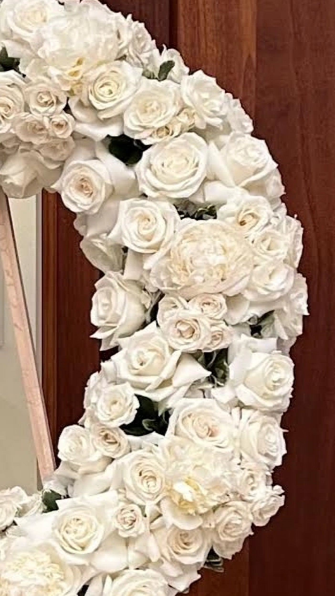 Floral wreath made of white roses against a wooden background