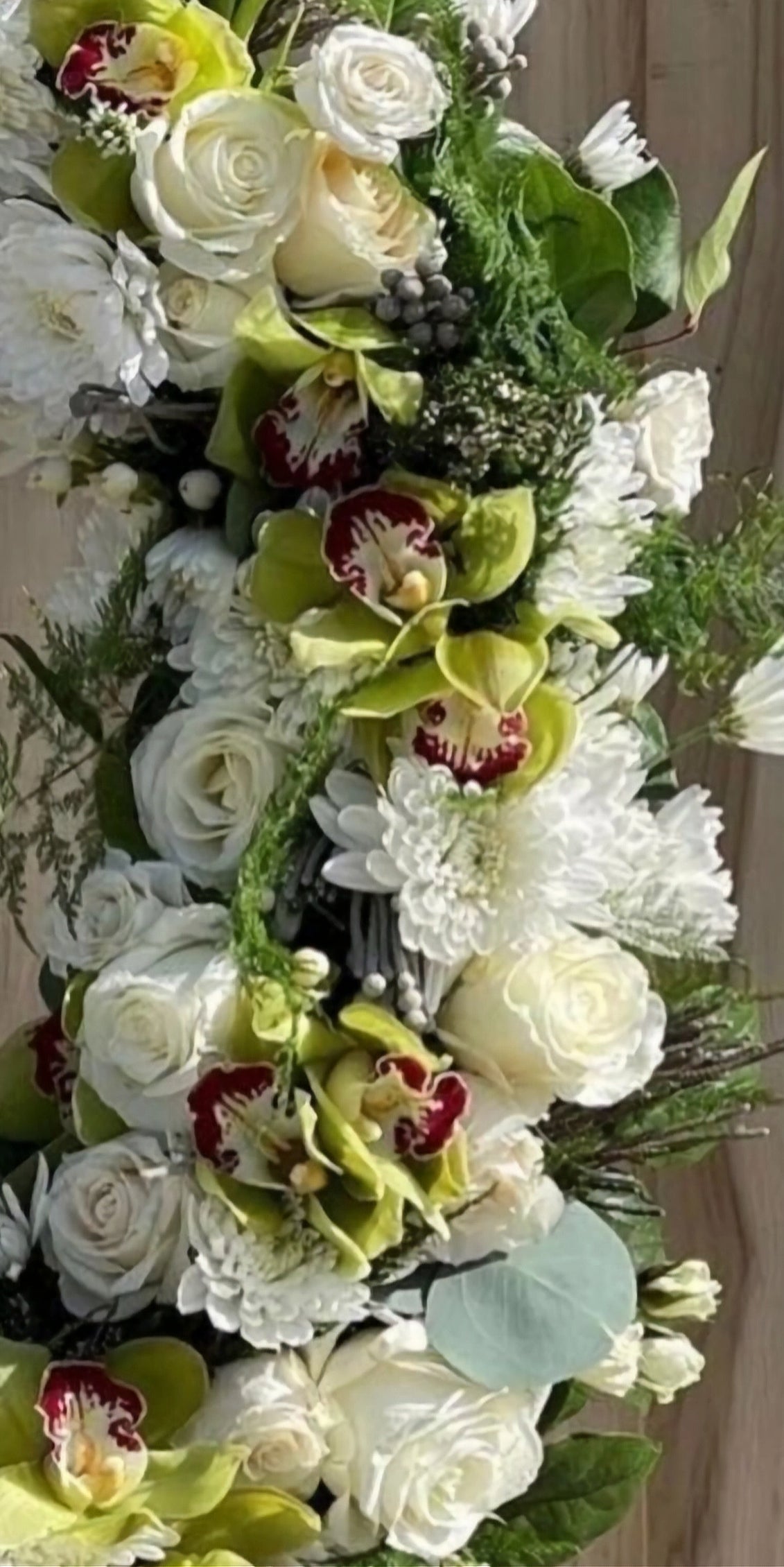 Floral arrangement with white roses, green orchids, and other flowers.