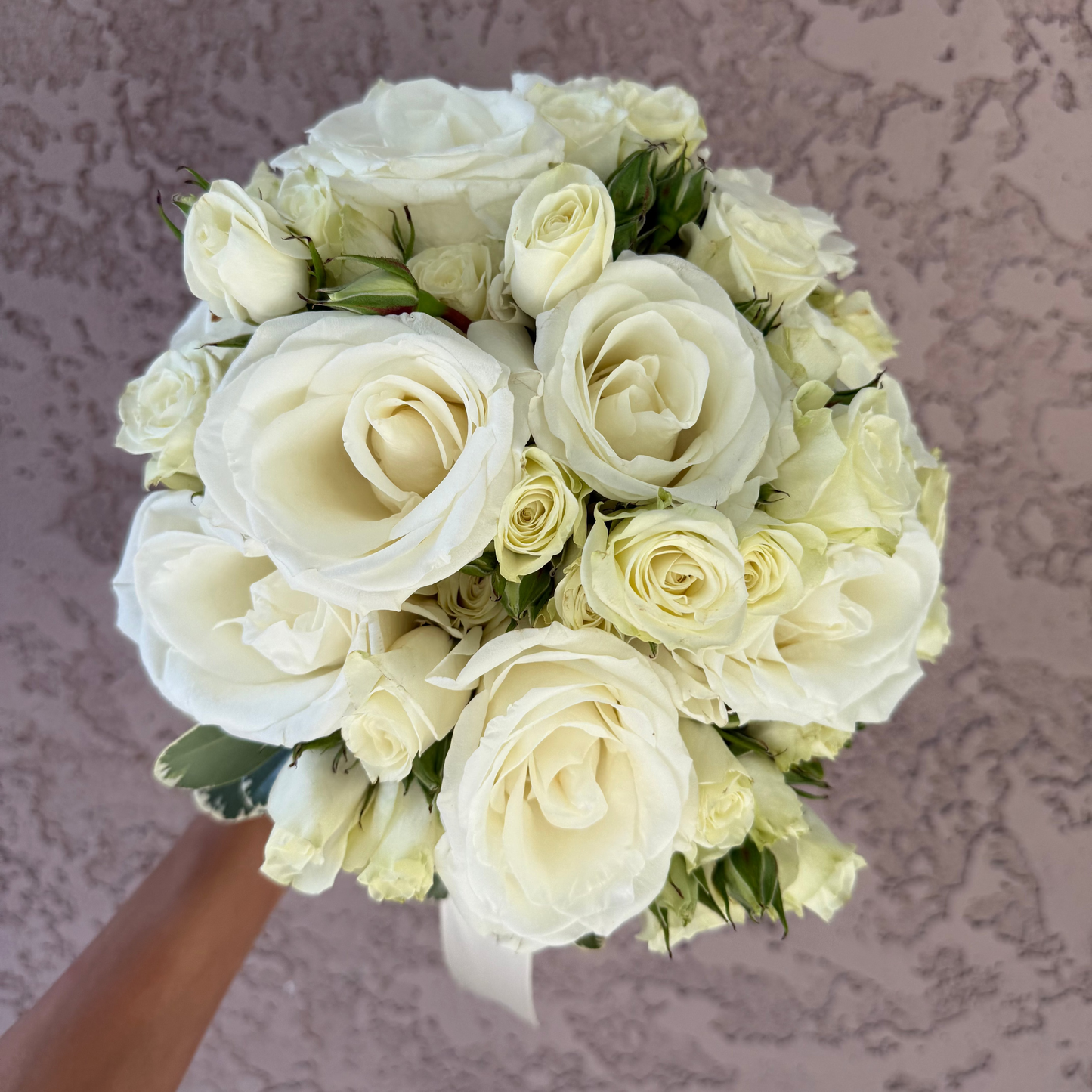 Bouquet of white roses held against a textured gray background
