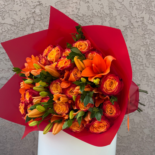 Bouquet of orange flowers wrapped in red paper on a gray background