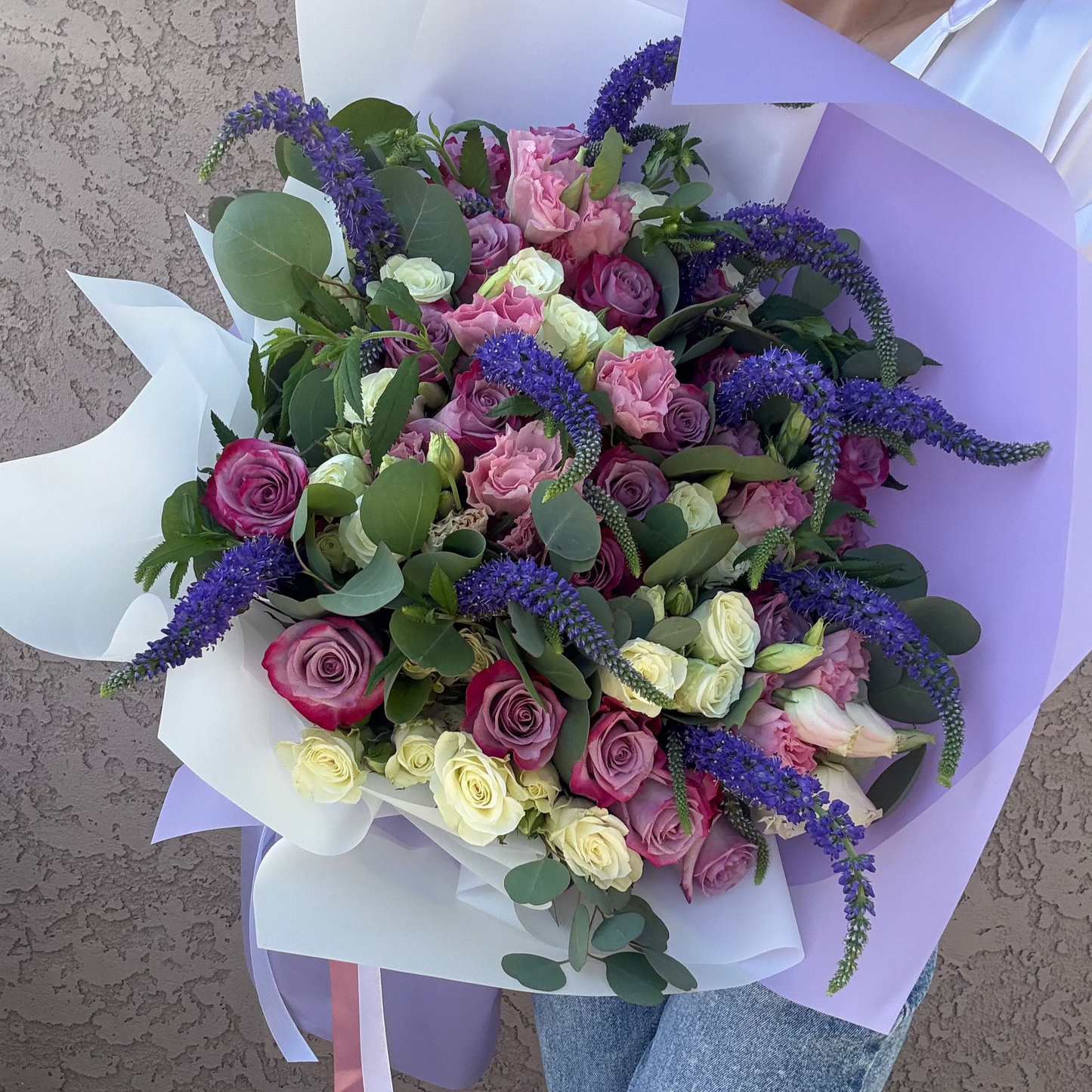 Bouquet of flowers held by a person with a neutral background