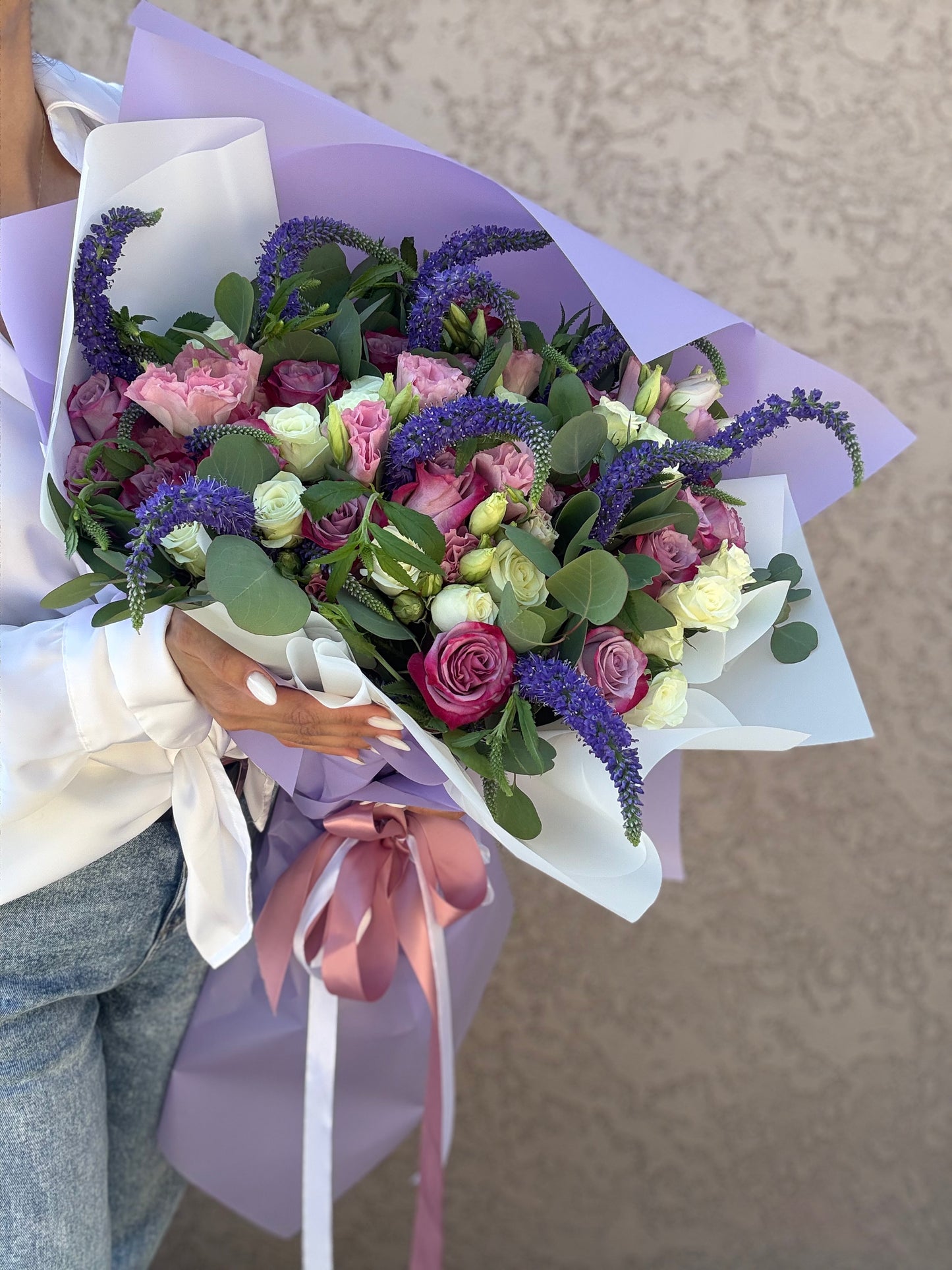Bouquet of flowers with a person holding it against a neutral background