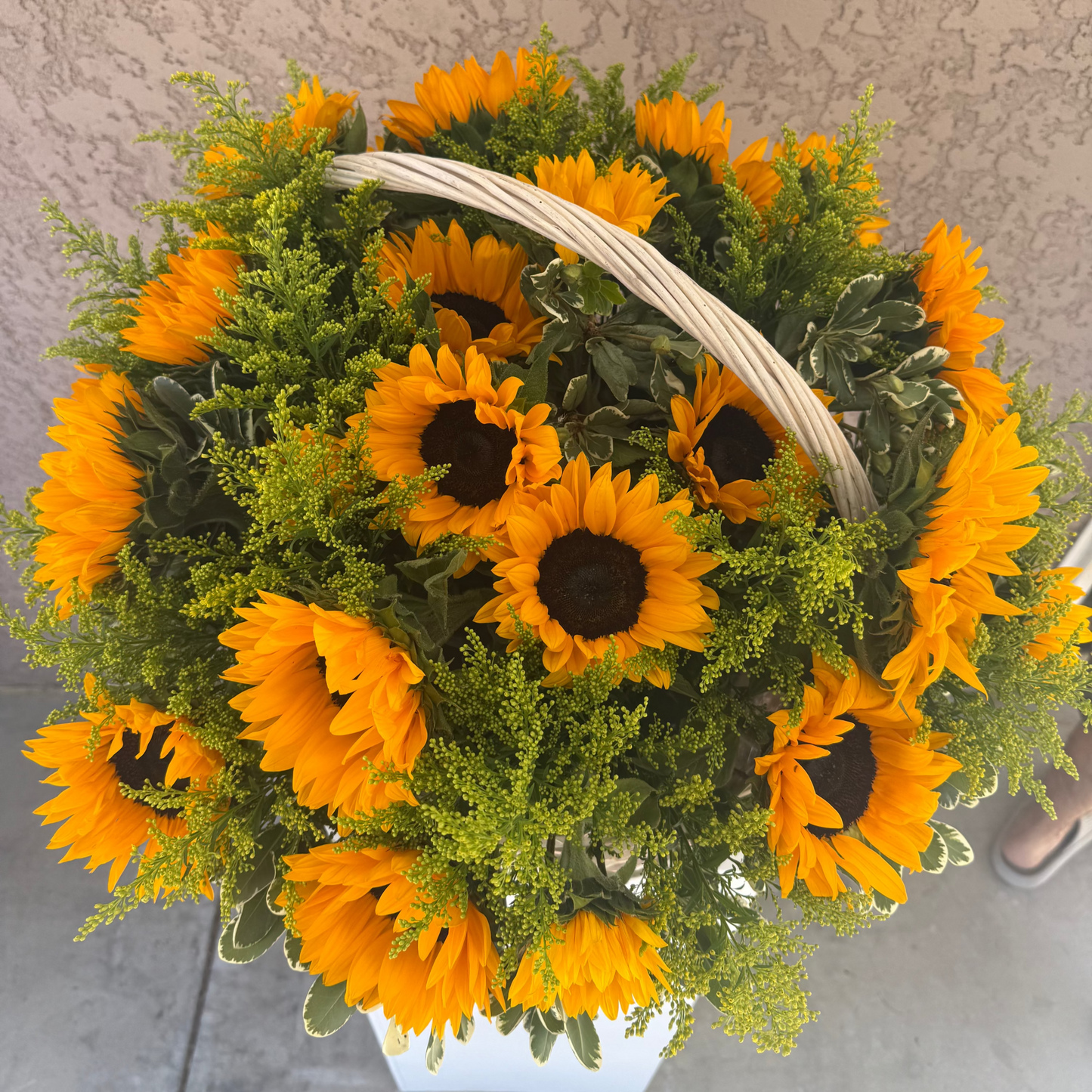 Bouquet of sunflowers in a white basket on a textured surface
