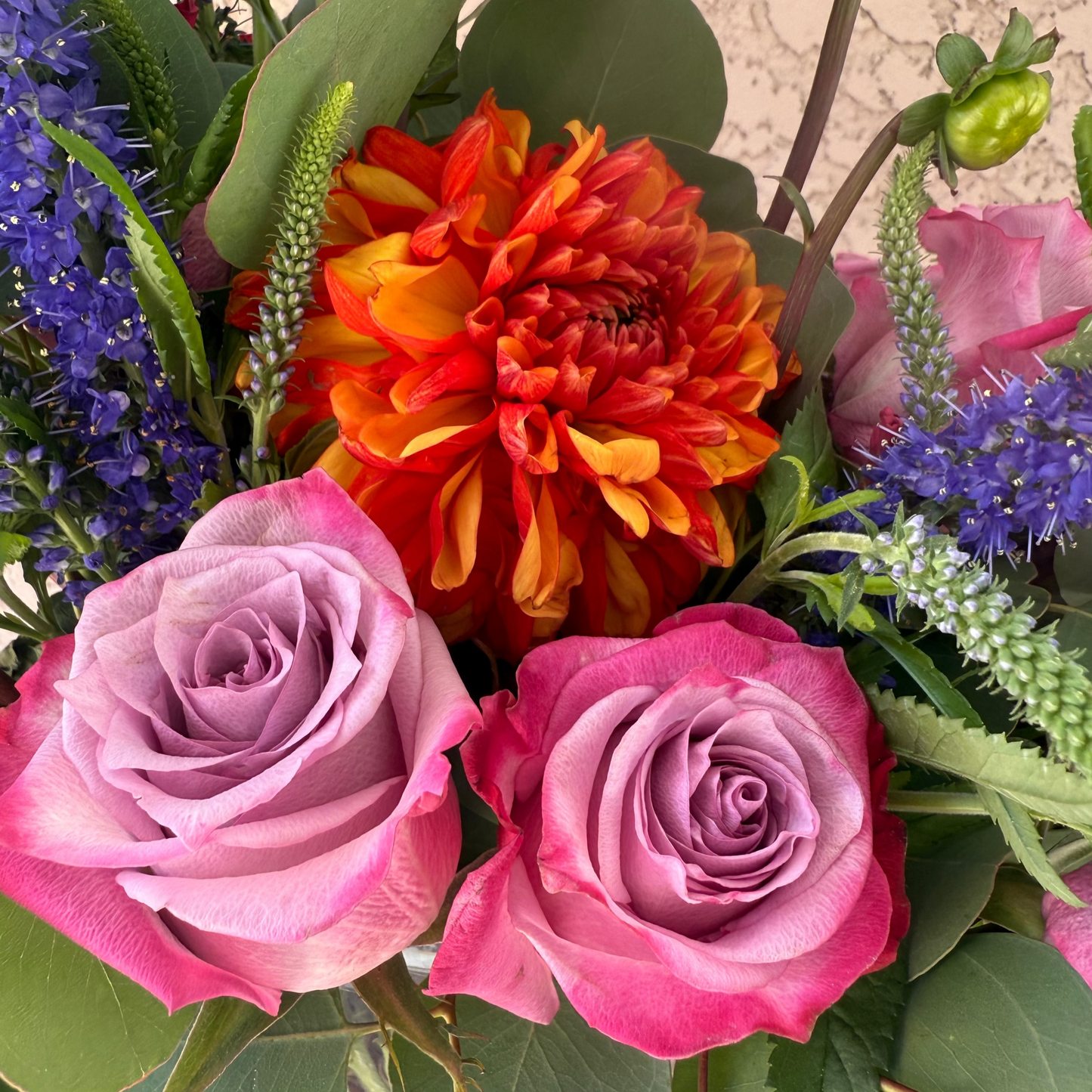 Bouquet of flowers including pink roses and a red-orange dahlia.