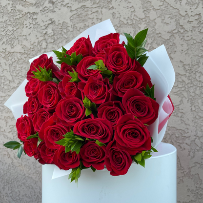 Bouquet of red roses wrapped in white paper against a neutral background