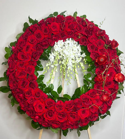 Floral wreath made of red roses with a central white flower arrangement on a light background