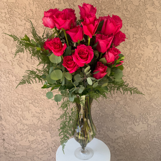 Bouquet of red roses in a clear vase on a beige background