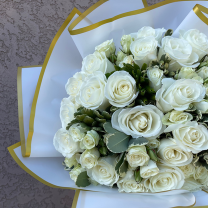 Bouquet of white roses in a decorative box with gold trim on a textured surface.