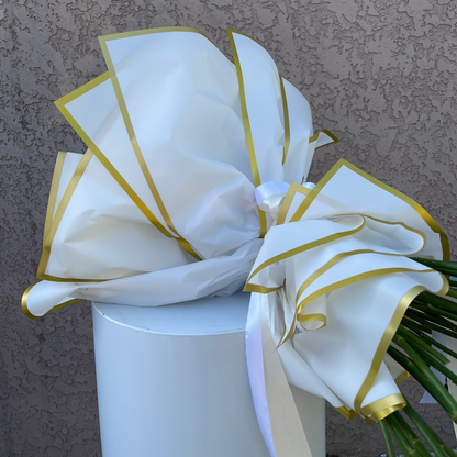 White bow with gold edges on a bouquet against a textured brown background