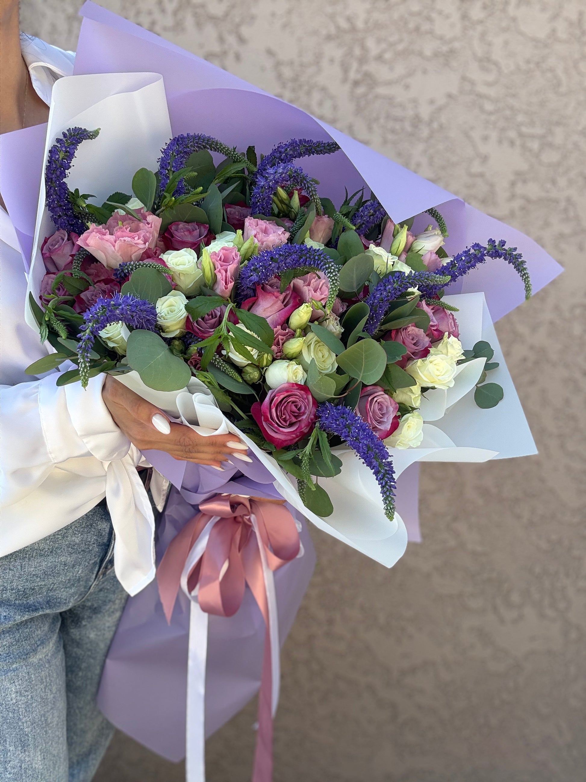 Bouquet of flowers with a person holding it against a neutral background