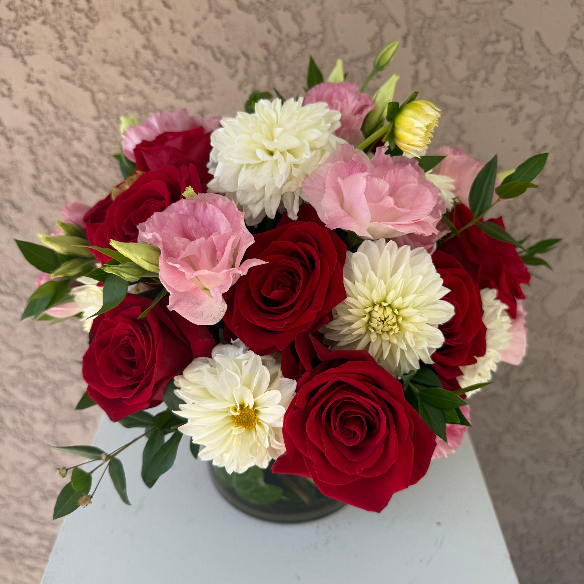 Bouquet of red roses, white and pink flowers on a light surface with a beige background