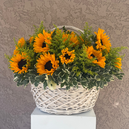 Basket of sunflowers on a white pedestal against a textured gray wall